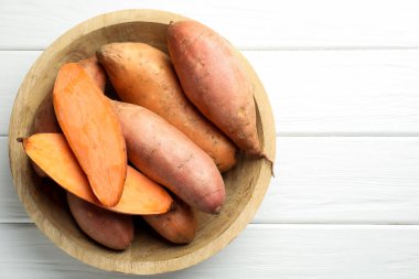 Beyaz ahşap masadaki kasede çiğ patates, üst manzara. Metin için boşluk