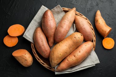 Siyah desenli masada çiğ patates, düz uzanmış.