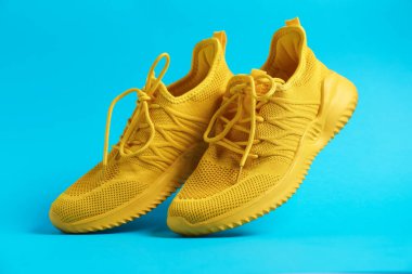 Açık mavi arka planda şık bir çift spor ayakkabı, yakın plan.