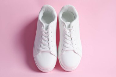 Pembe arka planda şık bir çift spor ayakkabı.