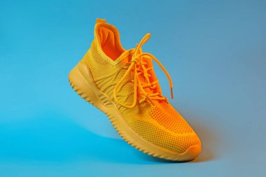 Açık mavi arka planda renkli şık bir spor ayakkabı, yakın plan.