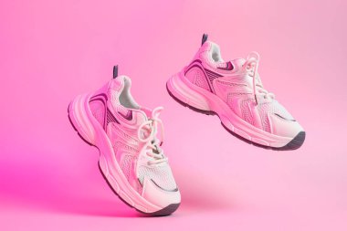 Pair of stylish sneakers in color light on pink background