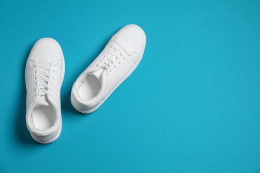 Pair of stylish sneakers on light blue background, top view. Space for text