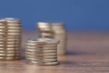 Ahşap masaya yığılmış bozuk paralar mavi arka plana karşı, yakın plan. Metin için boşluk