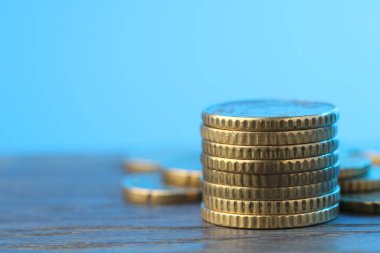 Açık mavi arkaplana karşı ahşap masaya para yığını, yakın plan. Metin için boşluk