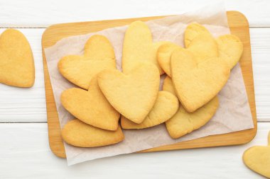 Lezzetli kalp şeklinde tereyağlı kurabiyeler beyaz ahşap masada, düz yatıyordu.