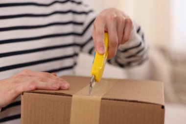 Kadın evinde bıçakla paketi açıyor, yakın plan.