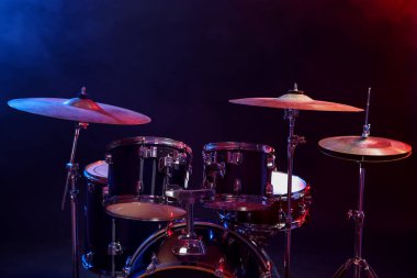 Davul seti koyu arkaplana karşı renk ışıklarıyla. Müzik aletleri