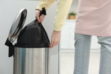 Mutfaktaki çöp kutusundan plastik poşet çıkaran kadın, yakın plan.
