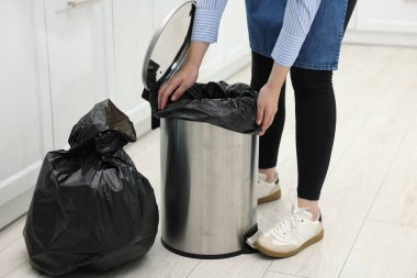Mutfaktaki çöp kutusuna plastik poşet koyan kadın, yakın plan.