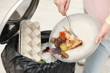 Mutfaktaki çöp kutusuna yemek atan kadın, yakın plan.