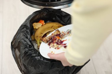 Mutfaktaki çöp kutusuna yemek atan kadın, yakın plan.