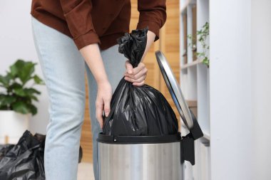 İçerideki çöp kutusundan plastik poşet çıkaran kadın, yakın plan.