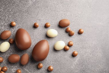 Paskalya kutlaması. Gri desenli masa üzerinde bir sürü çikolata yumurtası ve dragee, metin için boşluk ile düz yatıyordu.