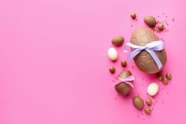 Pembe arka planda şekerli, çikolatalı Paskalya yumurtaları. Metin için boşluk