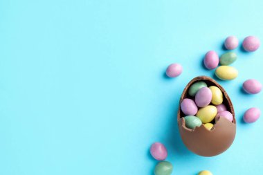 Paskalya kutlaması. Açık mavi arka planda şekerli kırık çikolata yumurtası, düz. Metin için boşluk
