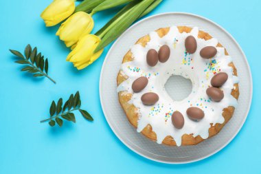 Lezzetli Paskalya pastası, güzel laleler ve açık mavi arka planda yeşil yapraklar.