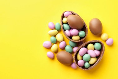 Mutlu Paskalyalar. Sarı arka planda renkli şekerlemeli leziz çikolatalı yumurtalar. Metin için boşluk