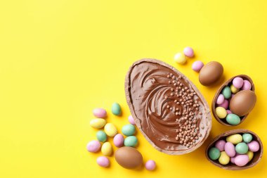 Mutlu Paskalyalar. Sarı arka planda renkli şekerlemeli leziz çikolatalı yumurtalar. Metin için boşluk