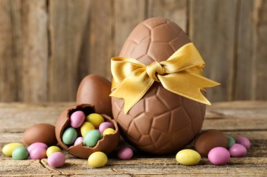 Ahşap masada renkli şekerlemeli lezzetli çikolata yumurtaları, yakın plan. Mutlu Paskalyalar