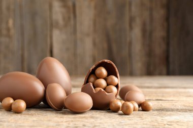 Mutlu Paskalyalar. Ahşap masada şekerli çikolatalı yumurtalar, yakın plan. Metin için boşluk