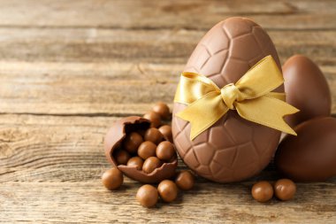 Mutlu Paskalyalar. Ahşap masada şekerli çikolatalı yumurtalar, yakın plan. Metin için boşluk