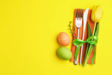 Paskalya kutlaması. Çiçekli masa dekoru ve sarı arka planda boyanmış yumurtalar, düz yatak. Metin için boşluk