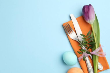 Paskalya kutlaması. Çiçekli masa dekoru ve açık mavi arka planda boyanmış yumurtalar. Metin için boşluk