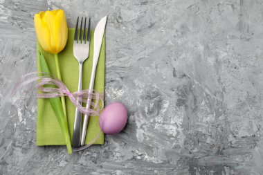 Paskalya sofrası. Güzel gümüş takımlar, lale ve gri arka planda boyanmış yumurta, üst manzara. Metin için boşluk