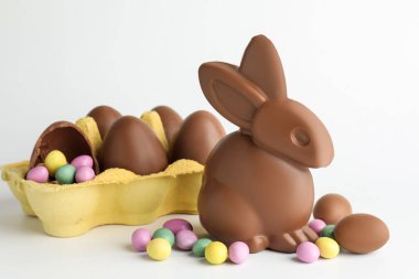 Çikolatalı Paskalya tavşanı, beyaz arka planda yumurta ve şeker.