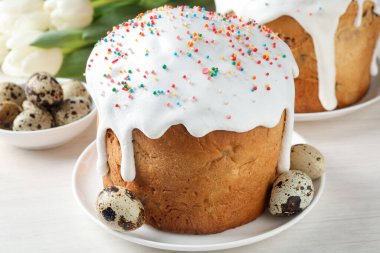 Güzel Paskalya pastaları, yumurtalar ve laleler beyaz masada, yakın plan.