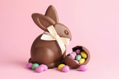 Çikolatalı Paskalya tavşanı ve pembe arka planda şekerli yumurta.