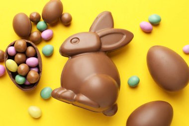 Çikolatalı Paskalya tavşanı ve sarı arka planda yumurtalar.