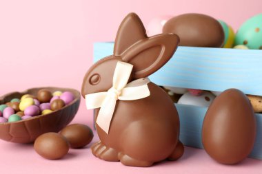 Çikolatalı Paskalya tavşanı ve pembe arka planda yumurtalar, yakın plan.