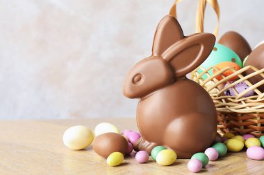 Çikolatalı Paskalya tavşanı ve hasır sepetteki yumurtalar açık gri arka planda, yakın plan. Metin için boşluk