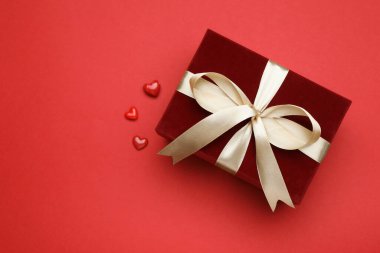 Sevgililer Günü. Güzel bir hediye ve kırmızı arka planda dekoratif kalpler, düz yatış. Metin için boşluk