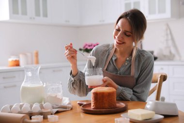 Genç bir kadın geleneksel paskalya pastasını mutfakta jöleli dekore ediyor.