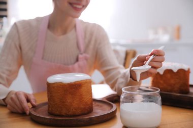 Geleneksel Paskalya pastasını mutfakta jöleli dekore eden genç bir kadın.