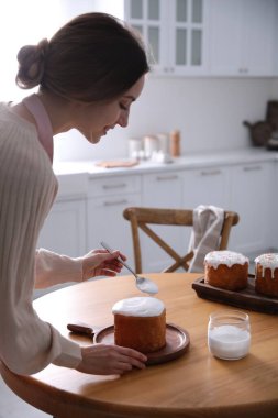 Genç bir kadın geleneksel paskalya pastasını mutfakta jöleli dekore ediyor.