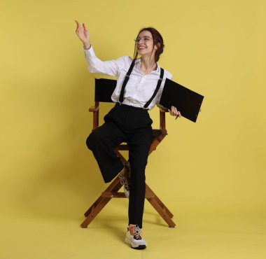 Profesyonel film yönetmeni, panosu sarı arka plandaki bir şeyi işaret ediyor.