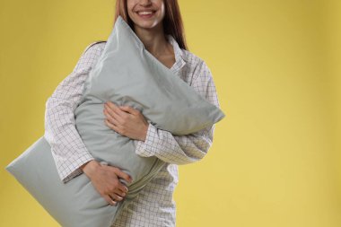 Sarı arka planda yastıklı şık pijamalı güzel bir kadın, yakın plan. Metin için boşluk