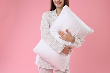 Pembe arka planda yastıklı şık pijamalı güzel bir kadın.
