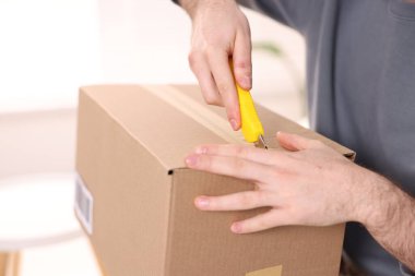 Evinde bıçakla paketi açan adam, yakın plan.