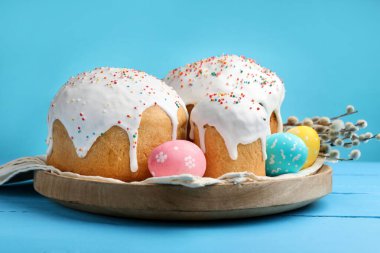 Lezzetli Paskalya pastaları, yumurtalar ve söğütler mavi ahşap masada.