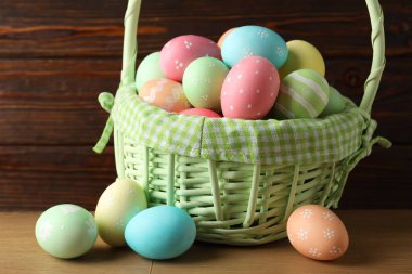 Güzel Paskalya yumurtaları sepetin içinde, ahşap masada, yakın plan.