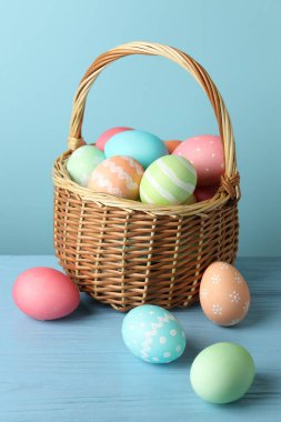 Masadaki sepetteki güzel Paskalya yumurtaları açık mavi arka planda