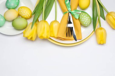 Paskalya kutlaması. Lale çiçekleri ve beyaz arka planda boyanmış yumurtalarla bembeyaz masa ayarları. Metin için boşluk