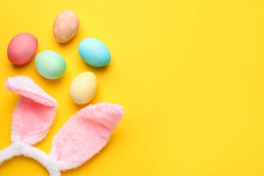 Mutlu Paskalyalar. Tatlı tavşan kulakları ve sarı arka planda boyanmış yumurtalar. Metin için boşluk