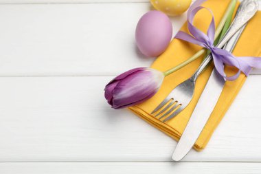 Paskalya sofrası. Lale ve beyaz ahşap arka planda boyanmış yumurtaları olan güzel gümüş takımlar, yakın plan. Metin için boşluk