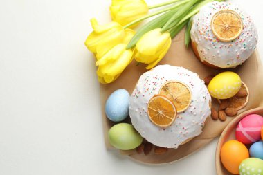 Lezzetli Paskalya pastaları, laleler ve beyaz masaya boyanmış yumurtalar. Metin için boşluk